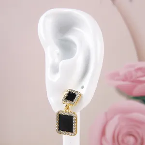 Vue macro de boucles d'oreilles carrées noires avec strass sur un modèle d'oreille