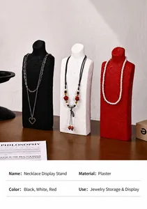 Macro detail of plaster bust necklace stands in black, white, and red on wood surface