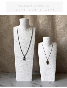 Detail view of astronaut and leaf necklaces on textured white bust jewelry stands