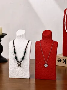 Close-up of elegant textured necklace display busts featuring a heart pendant and beads