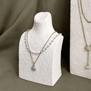 Elegant layered pearl and gold necklace displayed on a mannequin jewelry stand