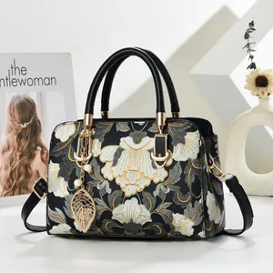Elegant floral embroidery handbag with leather handles and pearl leaf pendant details