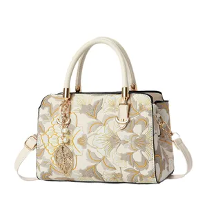 Elegant off-white Boston bag with floral embroidery and golden metal hardware