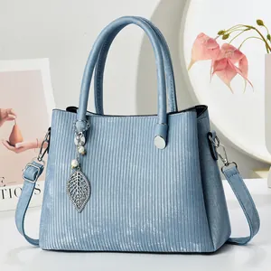 Light blue textured leather handbag with a leaf pendant and adjustable shoulder strap