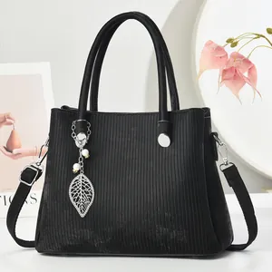 Chic black tote bag with vertical stripes and leaf pendant on a stylish background