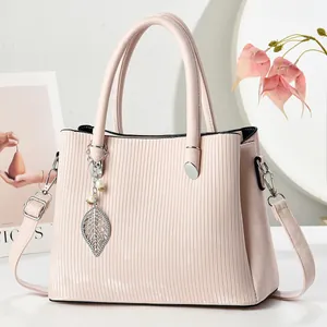 Pink pleated leather tote bag with leaf and pearl charm shown on a stylish background