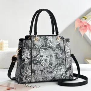 Elegant black and white printed tote bag with leather handles and gold-tone hardware