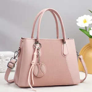 Light pink PU leather handbag with woven texture panel and round charm on gray background