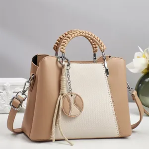 Détail du sac à bandoulière en cuir kaki et toile avec poignée tissée et pendentif