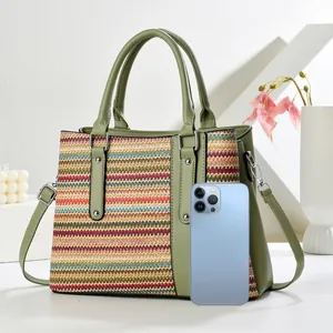 Detail of woven tote bag showing phone storage capacity and green leather stitching
