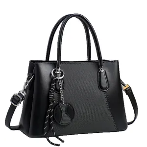 Minimalist black handbag with textured panels, dual handles and adjustable shoulder strap