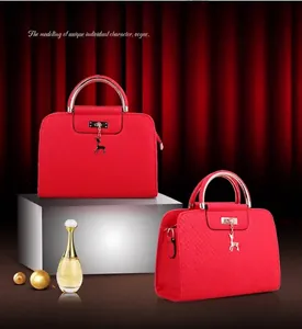 Detail of red embossed leather handbags with gold deer charm and metallic handle