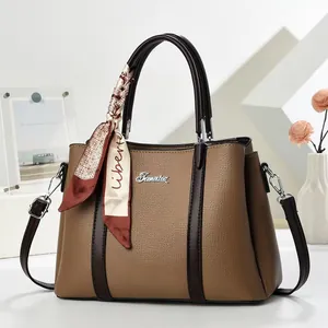 Detail of a brown lychee pattern leather tote bag with printed silk scarf and metal logo