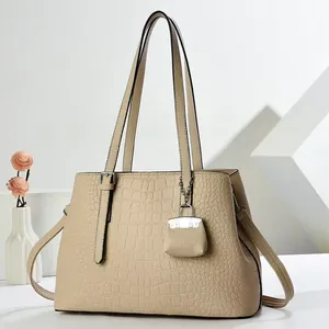 Beige faux crocodile skin tote bag with matching mini pendant on a minimalist background