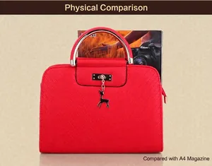 Detail of red PU leather handbag with deer pendant and metal handle next to A4 magazine
