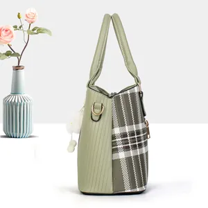 Light green textured tote bag with plaid side panels and a white plush pompom charm