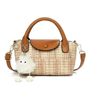Woven dumpling handbag with brown faux leather trim and white plush bird charm accent