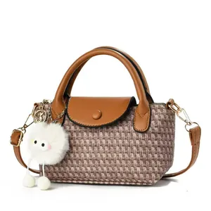 Woven dumpling handbag with brown leather handle and cute white plush charm accessory