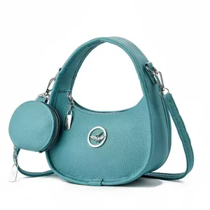 Détail du sac croissant bleu sarcelle en cuir grainé avec logo métallique