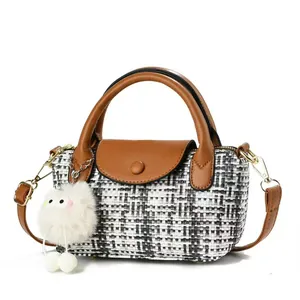 Black and white checkered woven crossbody bag with brown leather handles and plush charm