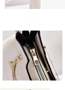Detail of high-gloss gold metal zipper pull on cream beige crossbody shell bag