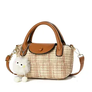 Detail of woven straw handbag featuring brown leather flap and cute plush bird charm