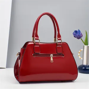 Detalle del bolso de charol rojo con herrajes dorados y bolsillo trasero con cremallera