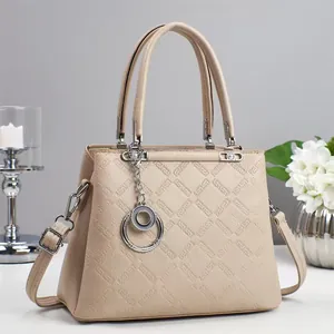 Dettaglio borsa beige in pelle trapuntata con ciondolo ad anelli e trama elegante