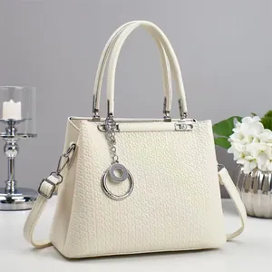 Detail of cream woven leather tote bag with silver ring charm and detachable shoulder strap