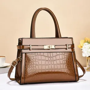 Detailed close-up of brown crocodile texture and gold metallic clasp on tote bag