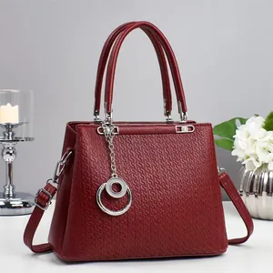 Detail of burgundy textured leather handbag with silver hardware in minimalist setup