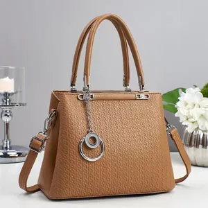 Close-up of brown tote bag showing geometric embossed texture and silver chain detail