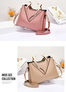 Detail of elegant shell bag with golden cat-ear metal handles and V-shaped trim accents