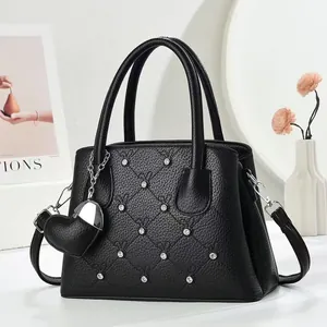 Elegant black leather handbag with diamond quilting, rhinestones, and heart pendant
