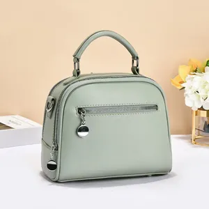 Detail of light green litchi texture handbag with silver round charm and zipper