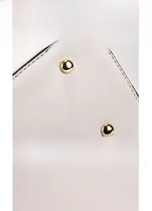 Close-up of white leather handbag bottom with golden metal studs and precise stitching