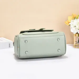Detailed bottom view of mint green leather handbag featuring four silver protective feet