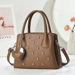 Detail of brown litchi pattern handbag with diamond stitching and silver metal rivets