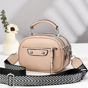 Detail of light beige triple-zip crossbody bag with geometric wide strap and rivet flap