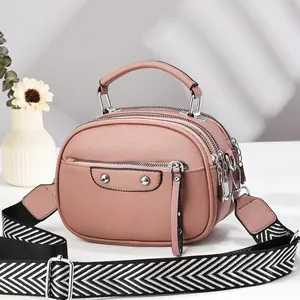 Detail view of pink triple-layer crossbody bag with textured leather and woven strap
