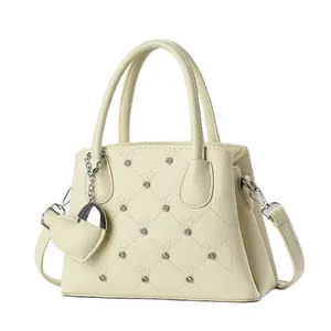 Elegant beige quilted leather handbag with silver studs and a heart charm accessory