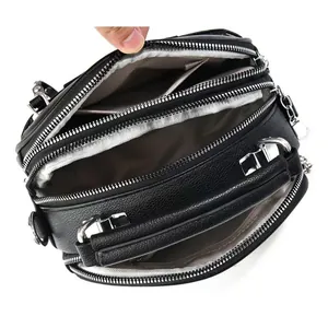 Detailed view of the three zipper compartments and gray lining of the black leather bag