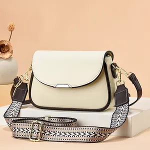 Sac bandoulière chic en cuir beige avec sangle ethnique sur socle géométrique