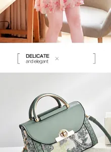 Detalle de bolso de cuero verde con aplique floral y asa de metal dorado