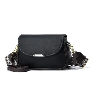 Détail du sac bandoulière en cuir grainé noir avec large bandoulière tissée et boucle argent