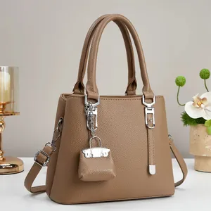 Detailweergave van bruine leren tas met zilveren hardware en kleine tasvormige hanger