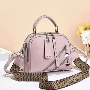 Detail of pink pebbled leather handbag with wide colorful herringbone pattern shoulder strap