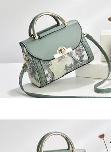 Detalle del bolso bandolera verde con estampado floral, asa metálica y textura trenzada