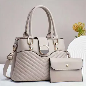 Detail of V-quilted faux leather handbag with metal magnetic closure and matching pouch