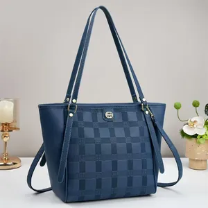 Detail of dark blue checkered tote bag featuring gold hardware and lychee grain leather